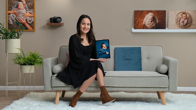 Course instructor Lidi Lima-Conlon in her photography studio, holding a newborn portrait album